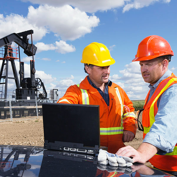 Industrial workers at oil rig with laptop
