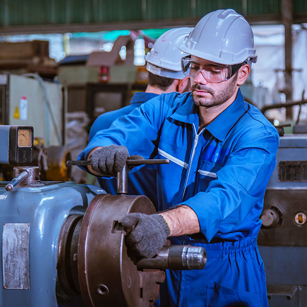 Male engineer working on machine in blue jumpsuit averted gaze